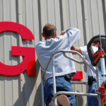 Workers,Install,A,Sign,On,The,Side,Of,An,Industrial